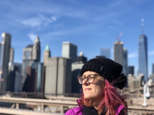 laura on the brooklyn bridge in front of the new york city skyline.