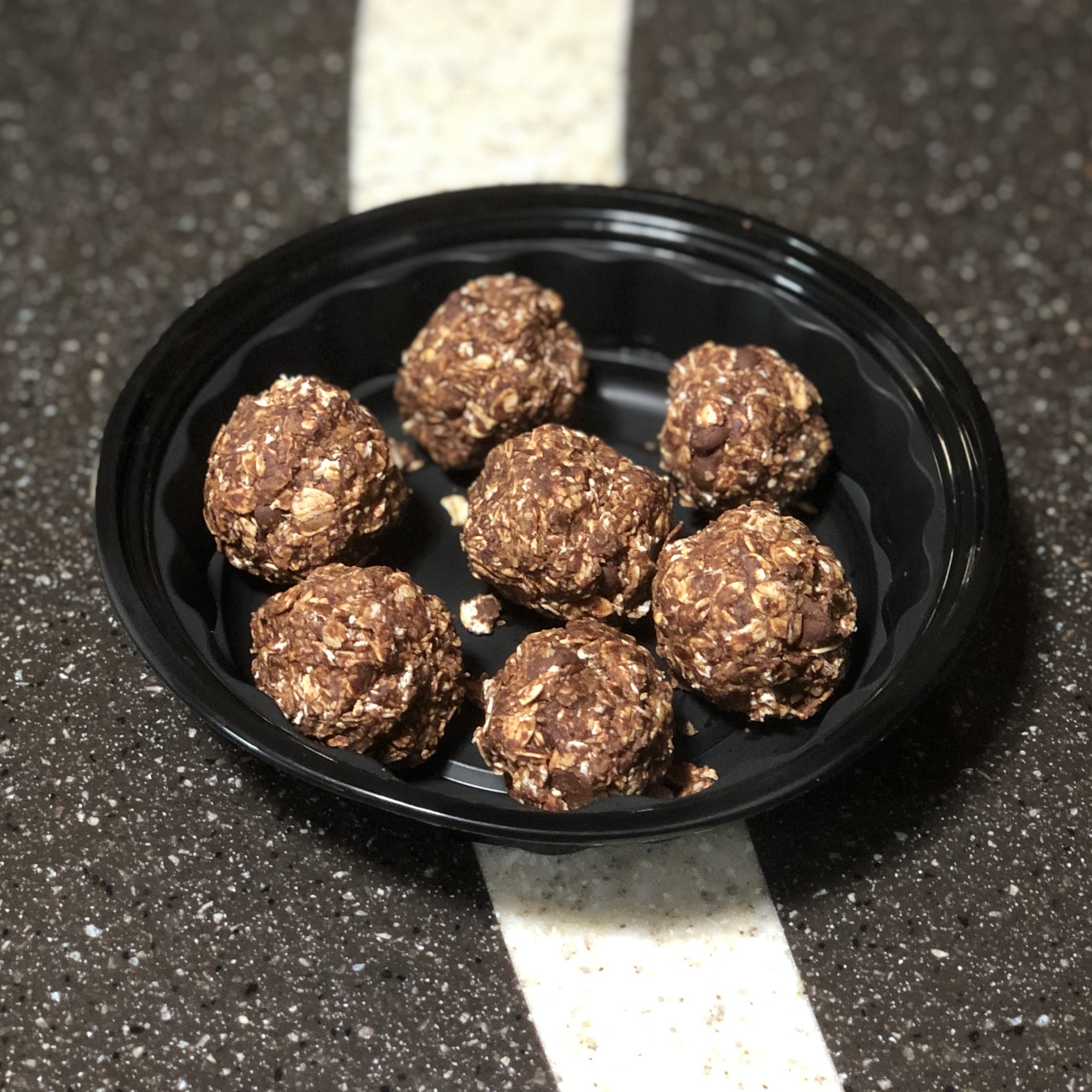 chocolate almond balls in a black bowl on a counter.