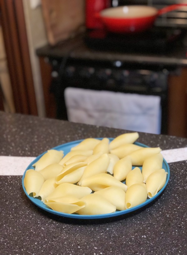 cooked jumbo pasta shells on a blue plate sitting on a counter in a kitchen.