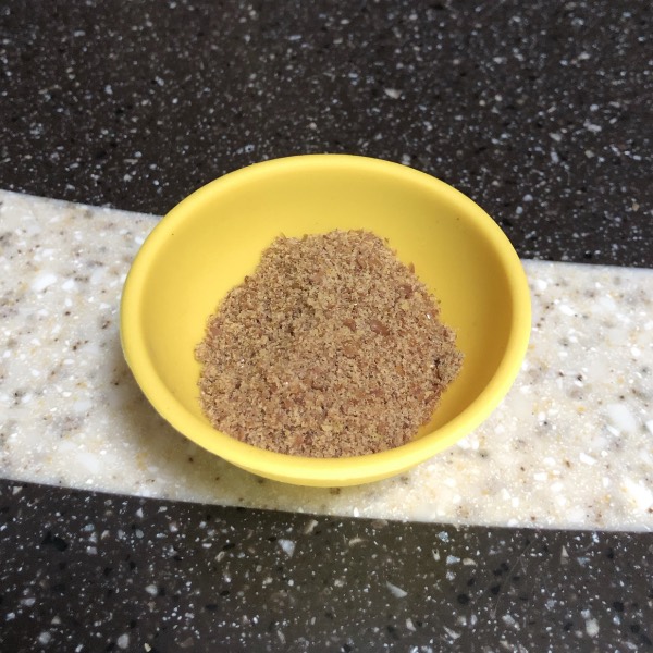 a small yellow bowl containing ground flaxseed sitting on a counter.