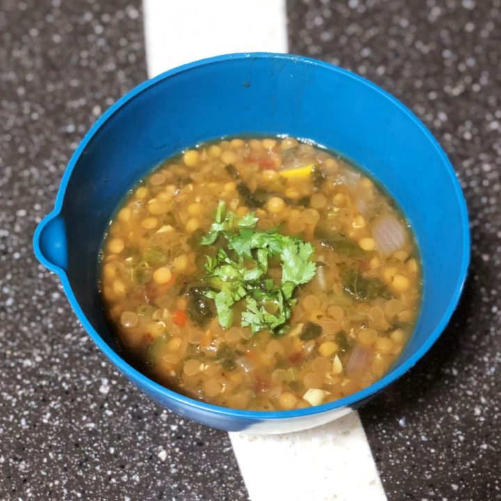 instant pot mexican lentil soup in a blue bowl on a counter.