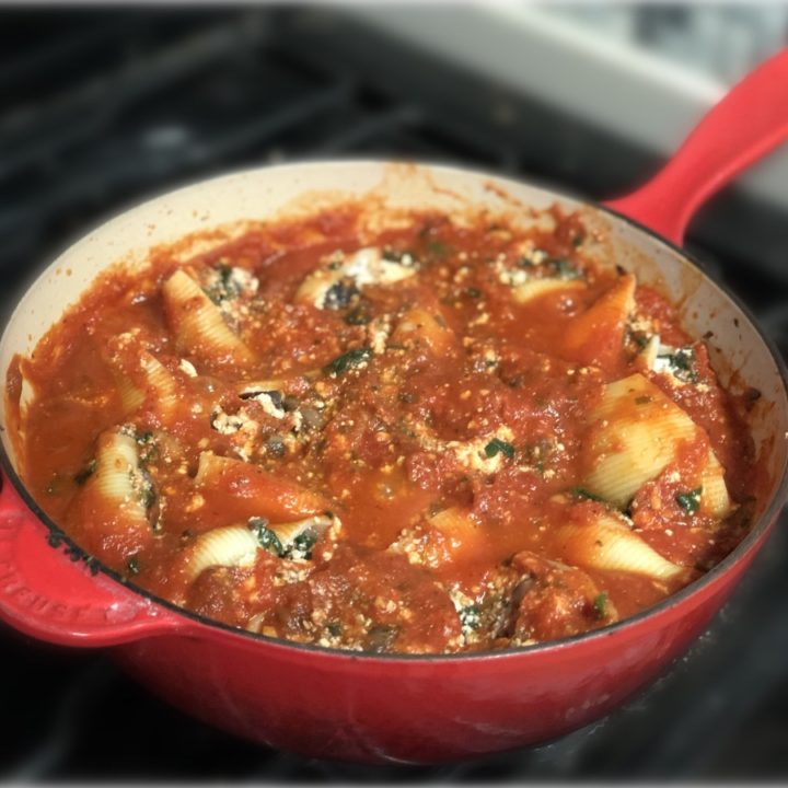 vegan skillet stuffed shells on a stovetop in a red pan.