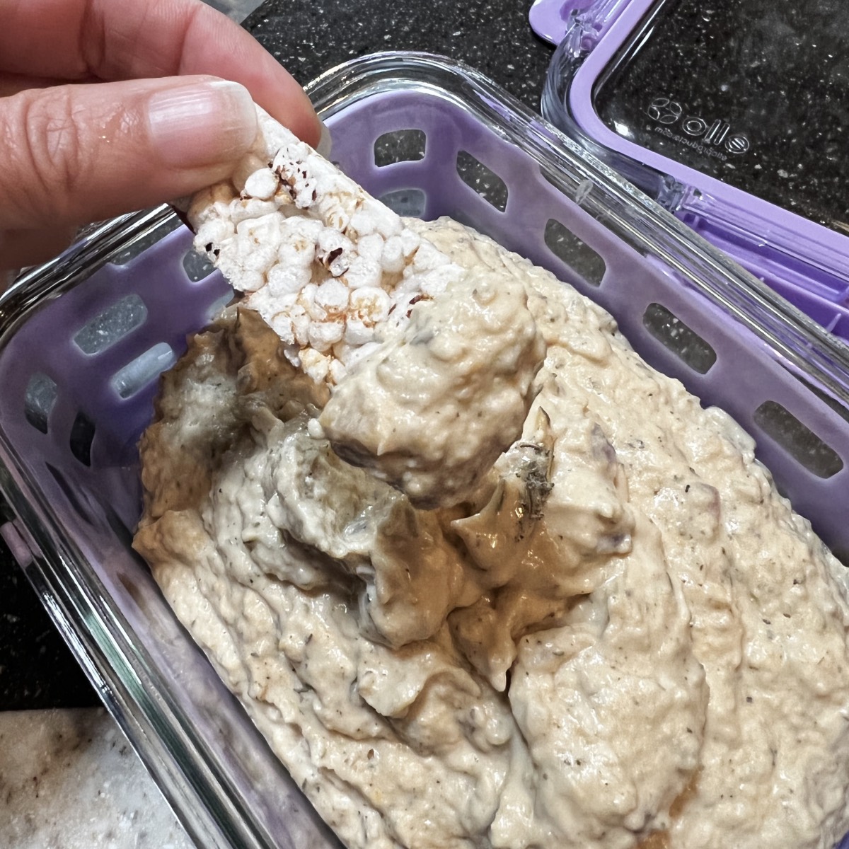 a glass meal prep container full of thanksgiving hummus with a cracker dipping into it.